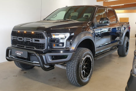 Black Ford F150 Raptor with a black bullbar in a showroom